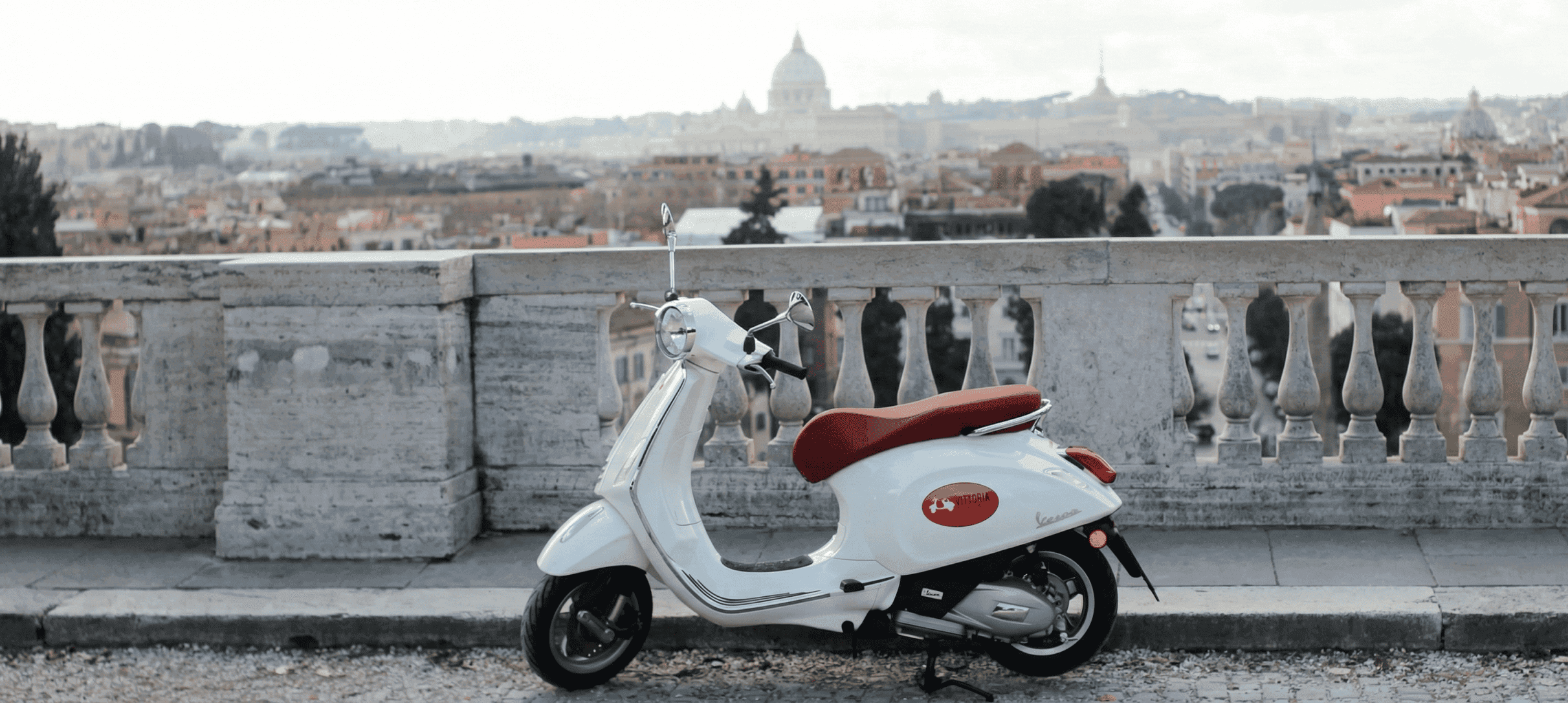 A white Vespa Primavera with the Rome skyline behind it
